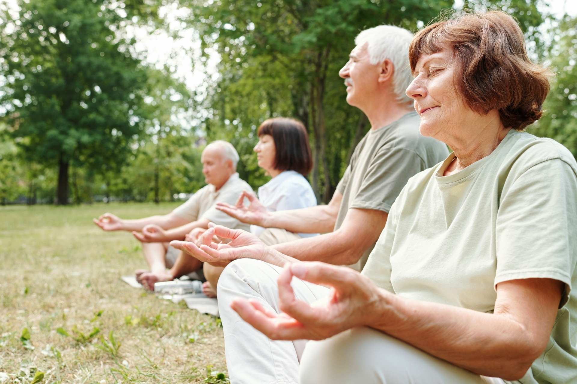 A group of seniors meditating outdoors together.
